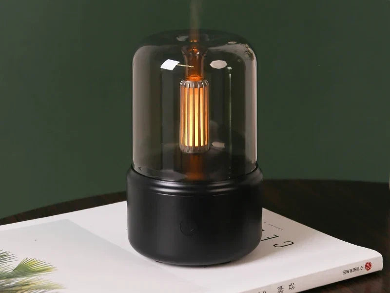 Lampe aromatique BRAISE Veilleuse au filament ambré, posée sur un livre