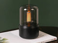 Lampe aromatique BRAISE Veilleuse au filament ambré, posée sur un livre